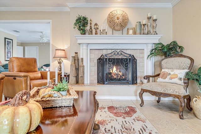 living area featuring a tiled fireplace, light tile patterned flooring, crown molding, and ceiling fan