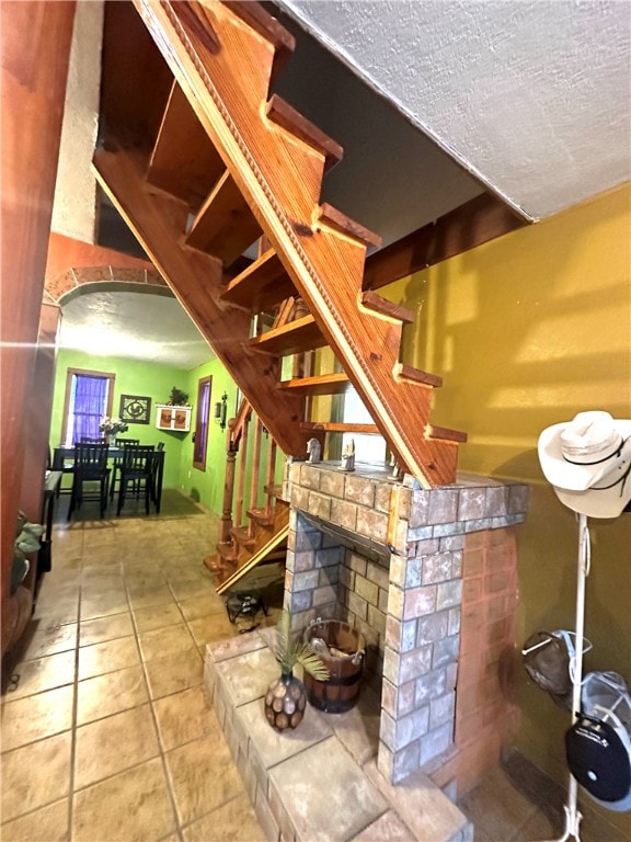 interior space featuring a fireplace, a textured ceiling, and tile patterned floors