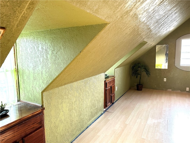 bonus room with light wood-type flooring and lofted ceiling