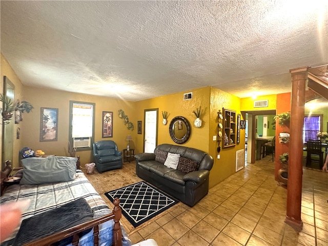 living room featuring cooling unit, a textured ceiling, light tile patterned floors, and ornate columns