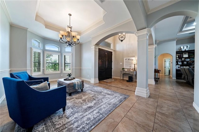 sitting room with a tray ceiling, an inviting chandelier, ornamental molding, and ornate columns