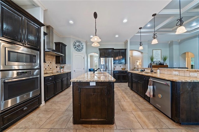 kitchen featuring wall chimney exhaust hood, crown molding, a spacious island, decorative light fixtures, and appliances with stainless steel finishes