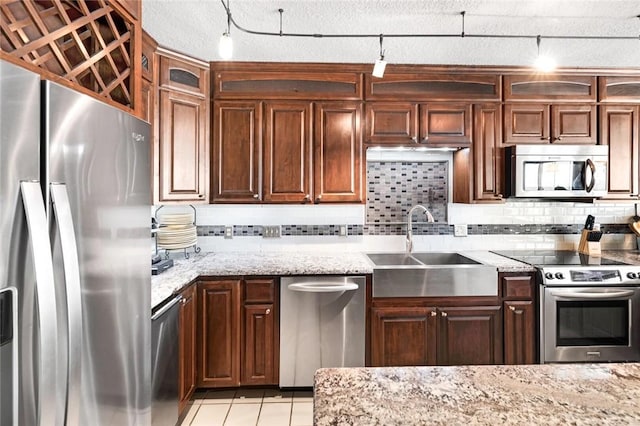 kitchen with tasteful backsplash, light tile patterned floors, light stone counters, appliances with stainless steel finishes, and a sink