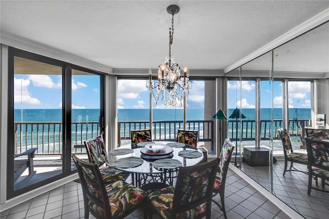 dining room featuring tile patterned floors, a water view, a chandelier, and expansive windows