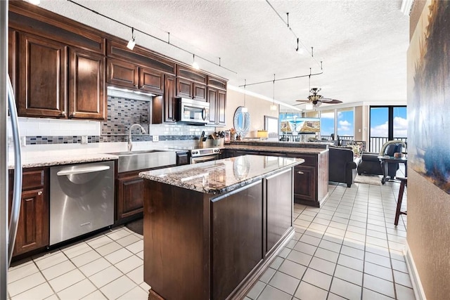 kitchen featuring backsplash, a kitchen island, stainless steel appliances, dark brown cabinetry, and a peninsula