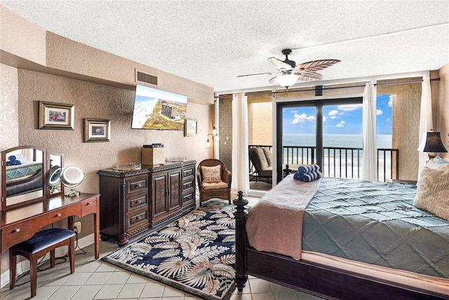 bedroom with access to exterior, visible vents, light tile patterned floors, a textured wall, and a textured ceiling