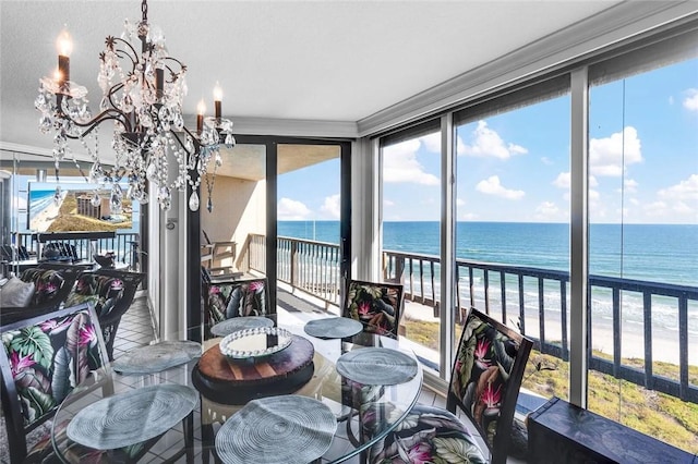 tiled dining space with a view of the beach, an inviting chandelier, and a water view