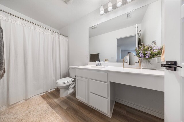 bathroom with wood-type flooring, vanity, and toilet