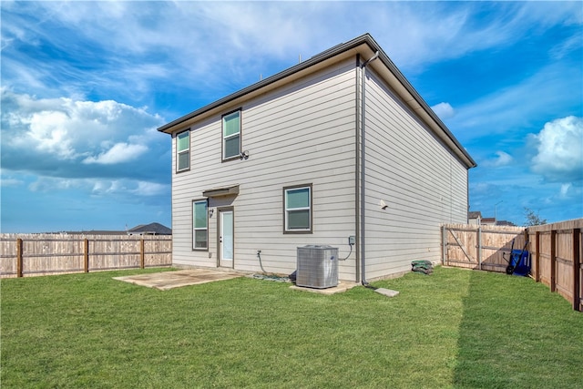 back of property with central AC unit, a patio area, and a yard