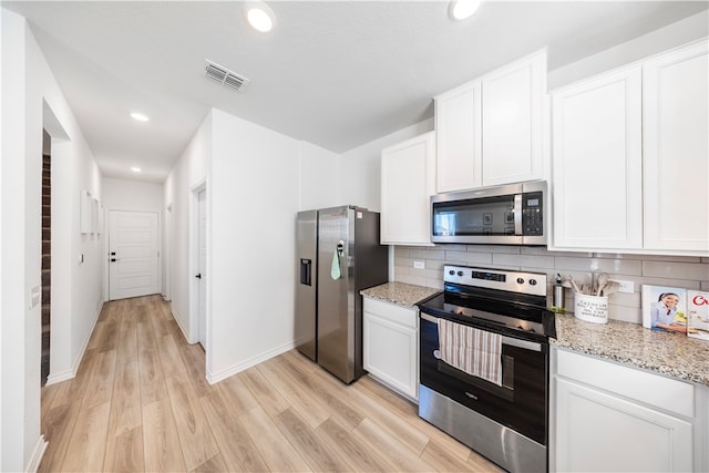 kitchen with white cabinetry, stainless steel appliances, light hardwood / wood-style floors, and light stone counters