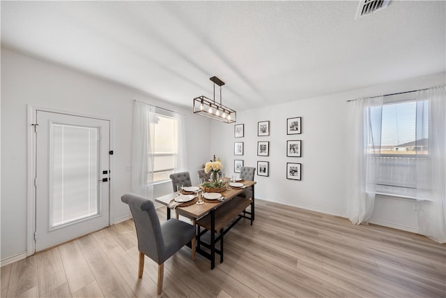 dining area with plenty of natural light, light hardwood / wood-style flooring, and a textured ceiling