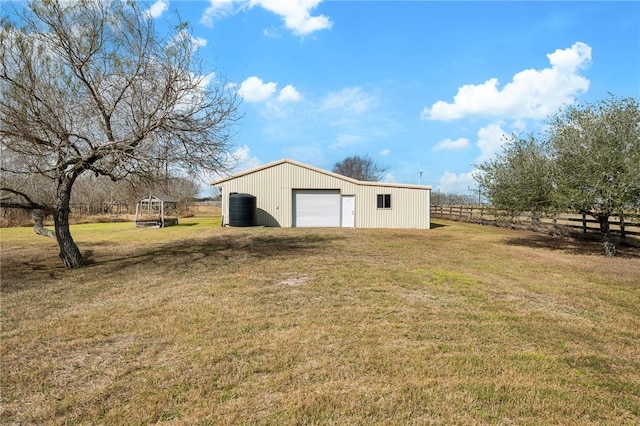 view of yard with an outbuilding, driveway, a detached garage, and fence