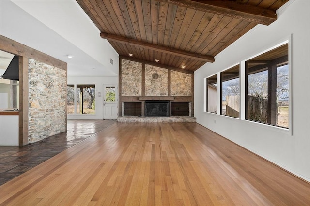 unfurnished living room featuring vaulted ceiling with beams, wood ceiling, hardwood / wood-style floors, and a stone fireplace