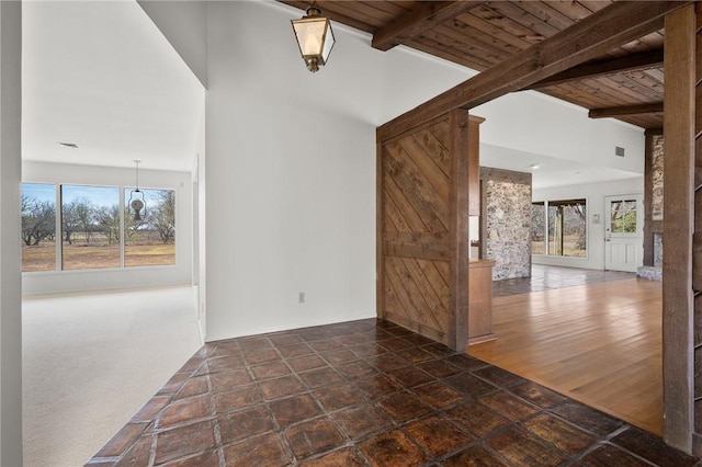 empty room with wooden ceiling, a wealth of natural light, and beamed ceiling