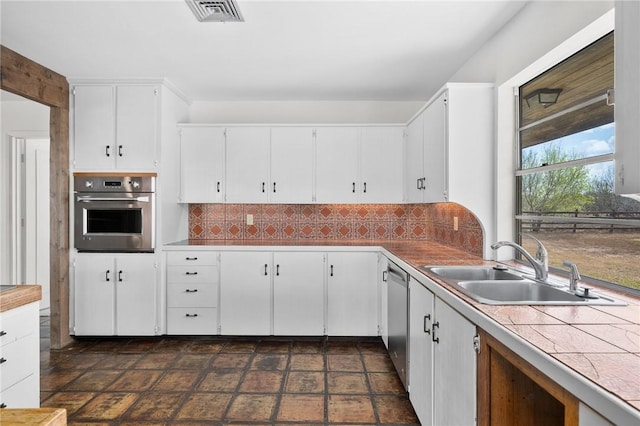 kitchen with a sink, white cabinetry, visible vents, appliances with stainless steel finishes, and decorative backsplash