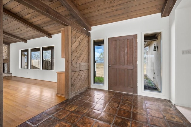 foyer with a stone fireplace, beam ceiling, and wood ceiling