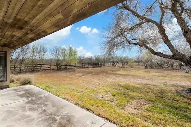 view of yard with a rural view, a patio area, and fence