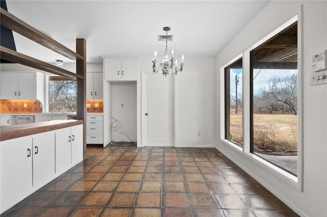 kitchen with visible vents, decorative backsplash, decorative light fixtures, white cabinetry, and a chandelier