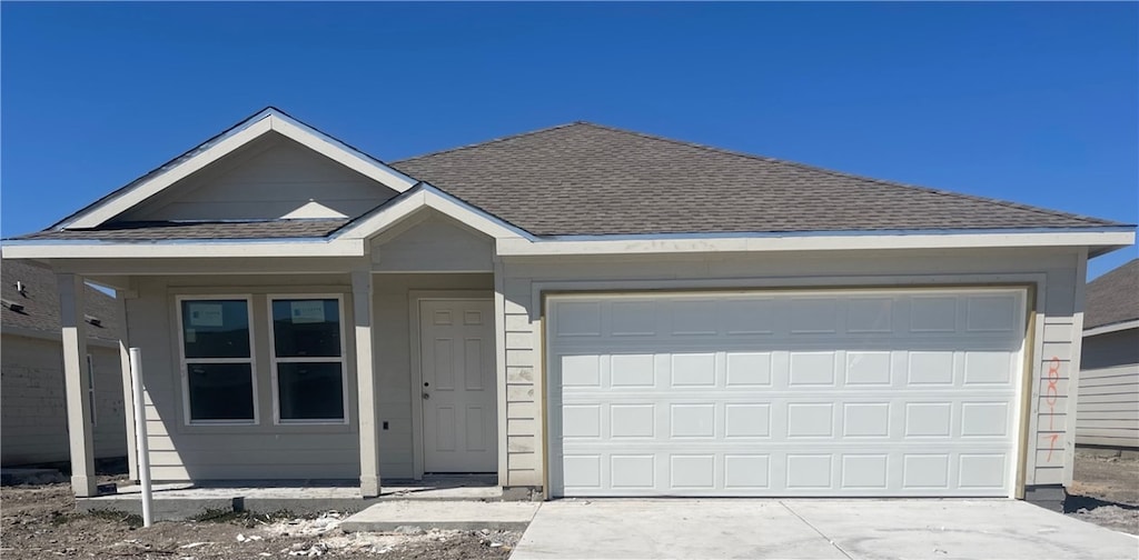 view of front of house with a garage, driveway, and a shingled roof