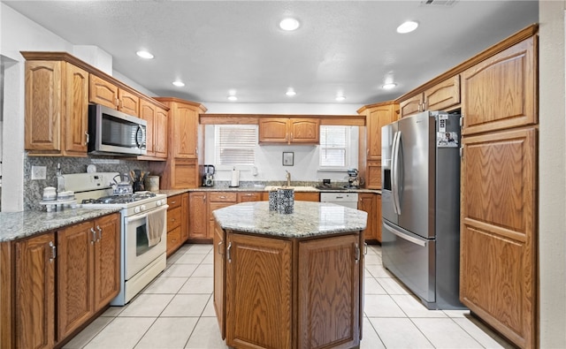 kitchen with a center island, sink, light stone countertops, and stainless steel appliances