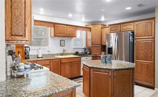 kitchen featuring stainless steel refrigerator with ice dispenser, white dishwasher, a kitchen island, and a healthy amount of sunlight