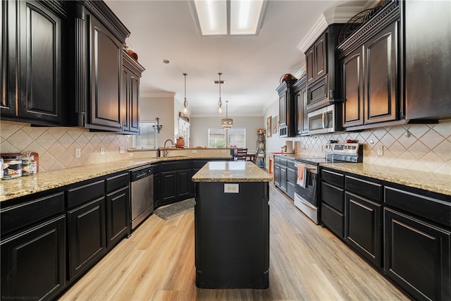 kitchen with appliances with stainless steel finishes, decorative light fixtures, crown molding, a center island, and light wood-type flooring