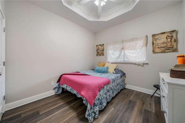 bedroom featuring ceiling fan, dark hardwood / wood-style floors, a tray ceiling, and ornamental molding