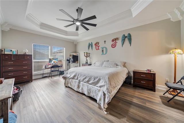 bedroom with ceiling fan, wood-type flooring, ornamental molding, and a tray ceiling