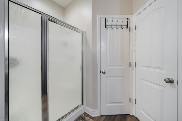 bathroom with hardwood / wood-style flooring and a shower with door