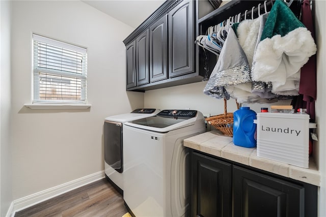 clothes washing area featuring cabinets, washing machine and dryer, and dark wood-type flooring