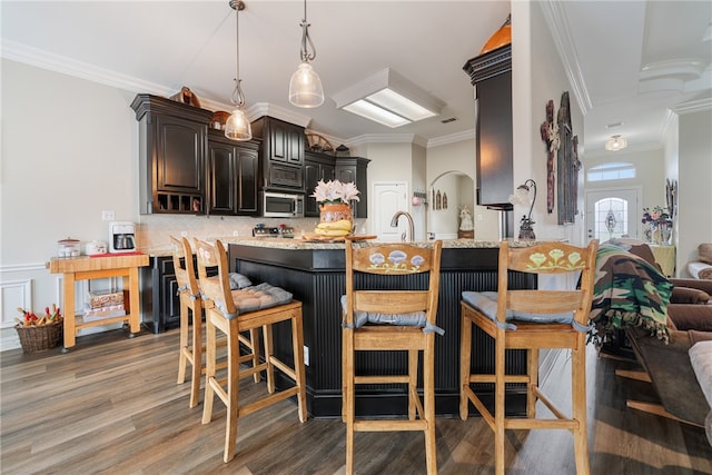 kitchen with ornamental molding, a kitchen breakfast bar, kitchen peninsula, and hardwood / wood-style flooring