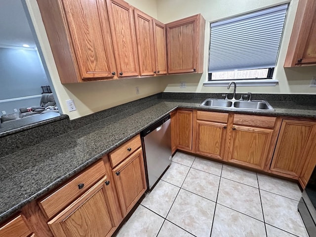 kitchen with light tile patterned flooring, stainless steel dishwasher, dark stone counters, and sink