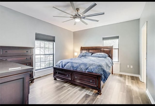 bedroom with multiple windows, ceiling fan, and light hardwood / wood-style floors