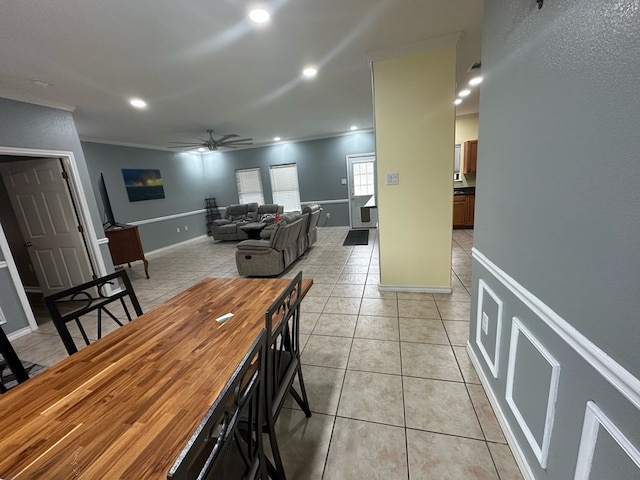 tiled dining area featuring ceiling fan and crown molding