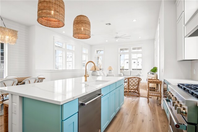 kitchen featuring stainless steel appliances, sink, light hardwood / wood-style floors, a kitchen island, and hanging light fixtures