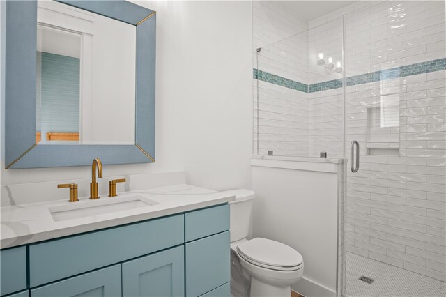 bathroom featuring vanity, toilet, and a shower with door