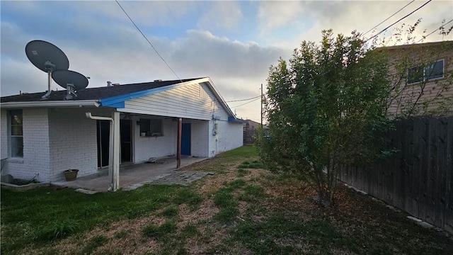 rear view of house featuring brick siding, a fenced backyard, a lawn, and a patio