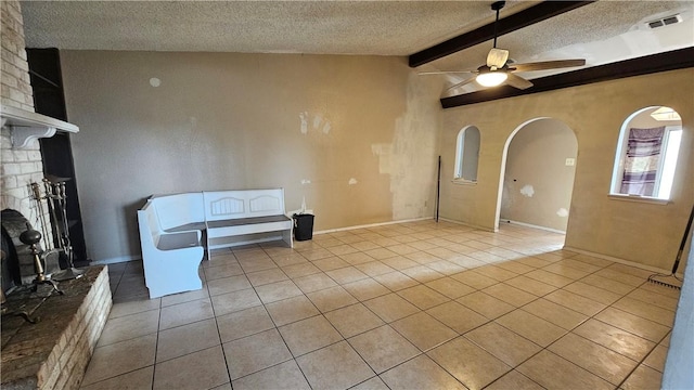 interior space featuring ceiling fan, light tile patterned floors, lofted ceiling with beams, and a textured ceiling