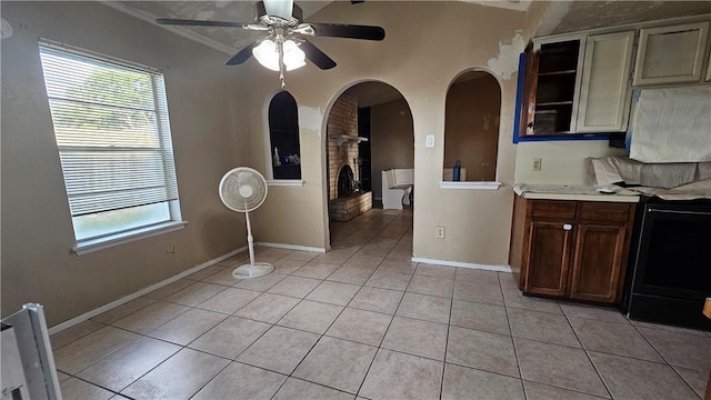 kitchen featuring ceiling fan, light tile patterned floors, a fireplace, and a wealth of natural light