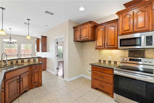 4529 Ballad Tree Dr, Corpus Christi, TX 78410 - kitchen with appliances with stainless steel finishes, decorative backsplash, a chandelier, pendant lighting, and brown cabinets