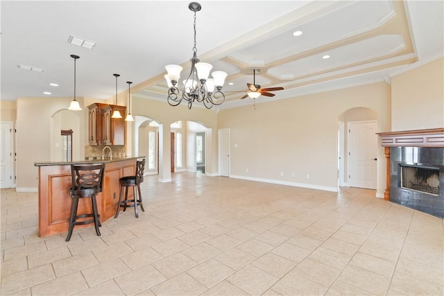 4529 Ballad Tree Dr, Corpus Christi, TX 78410 - kitchen with arched walkways, coffered ceiling, ceiling fan, a tile fireplace, and a kitchen bar