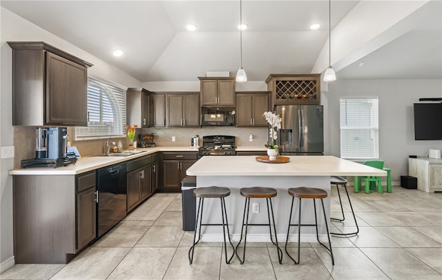 6754 Mikayla St, Corpus Christi, TX 78413 - kitchen with black appliances, vaulted ceiling, a breakfast bar area, decorative backsplash, and a kitchen island