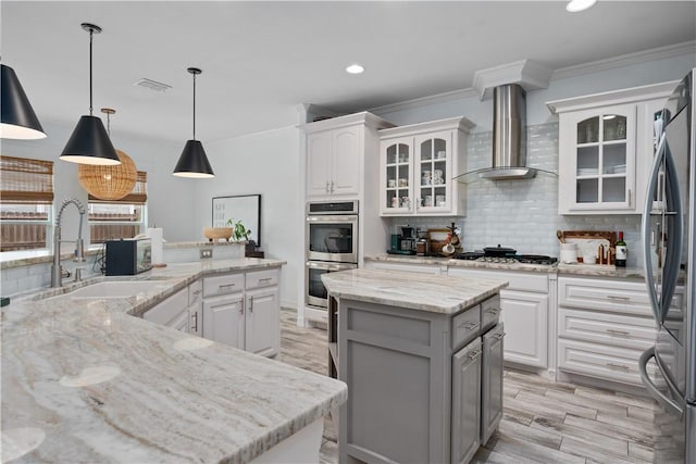 15114 Barataria Dr, Corpus Christi, TX 78418 - kitchen featuring wall chimney exhaust hood, a kitchen island, appliances with stainless steel finishes, crown molding, and tasteful backsplash