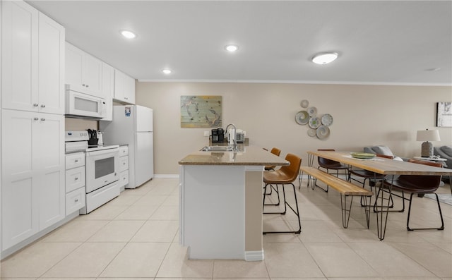 kitchen featuring light tile patterned floors, a breakfast bar area, white appliances, white cabinets, and sink