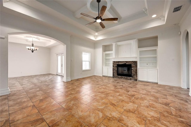 unfurnished living room featuring ceiling fan with notable chandelier, built in features, a fireplace, a tray ceiling, and crown molding