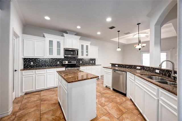 kitchen with pendant lighting, sink, white cabinets, a center island, and stainless steel appliances