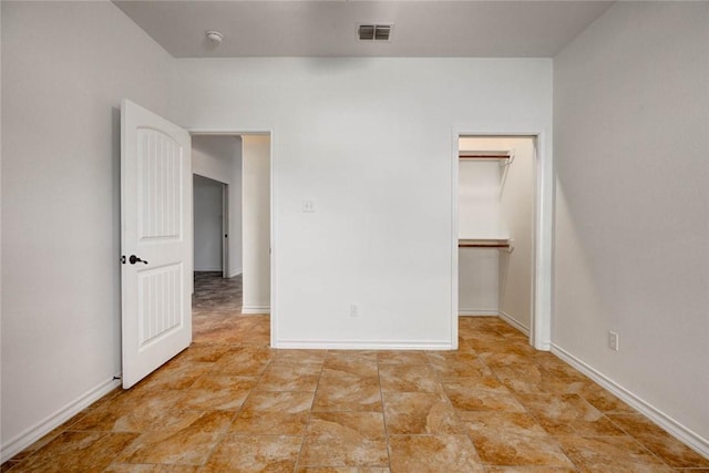 unfurnished bedroom featuring a walk in closet and a closet