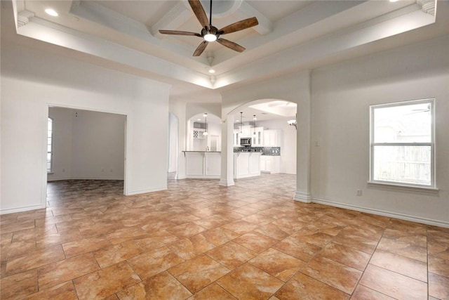 unfurnished living room with crown molding, a tray ceiling, ceiling fan, and a high ceiling