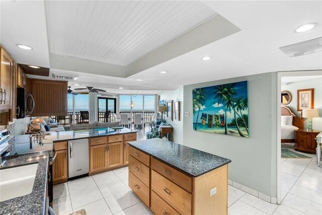 kitchen featuring sink, a center island, light tile patterned floors, appliances with stainless steel finishes, and a raised ceiling