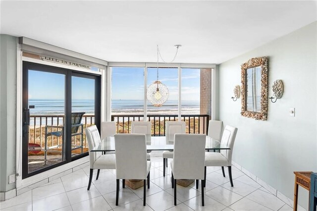 dining area with light tile patterned floors, floor to ceiling windows, a beach view, and a water view